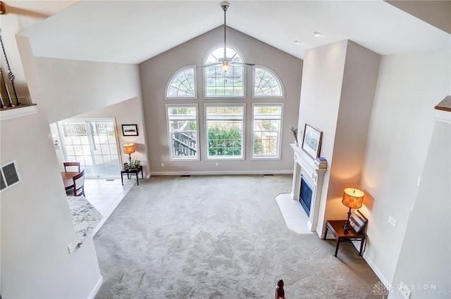 living room featuring ceiling fan, high vaulted ceiling, and light colored carpet