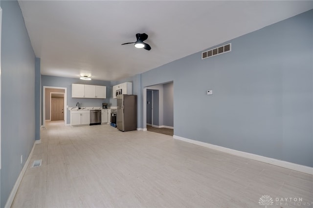 unfurnished living room featuring sink, light hardwood / wood-style floors, and ceiling fan