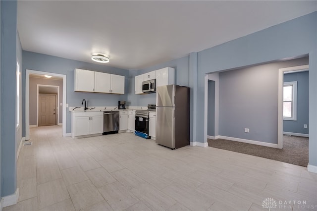 kitchen with appliances with stainless steel finishes, sink, and white cabinets