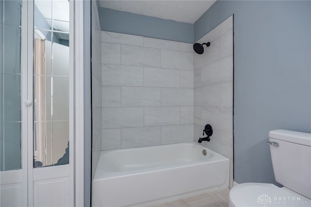 bathroom featuring toilet and tiled shower / bath