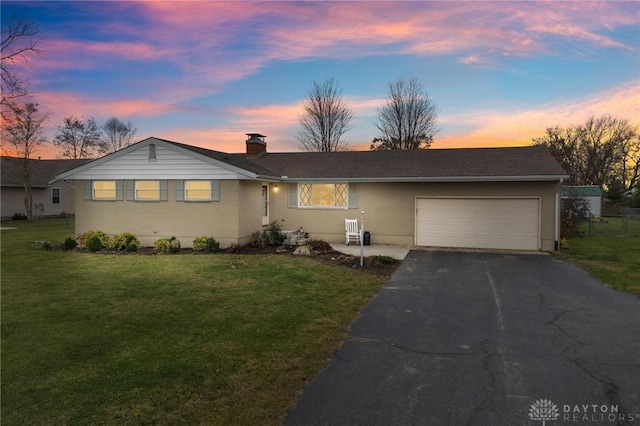 ranch-style home featuring a garage and a lawn