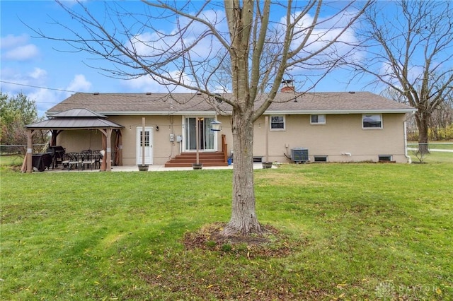 back of property with a gazebo, cooling unit, and a lawn