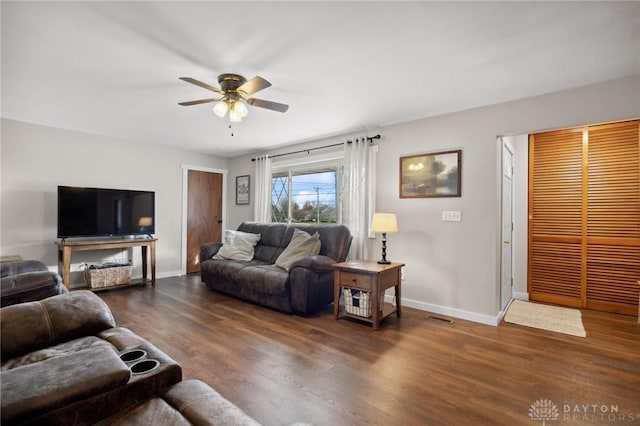 living room featuring ceiling fan and dark wood-type flooring