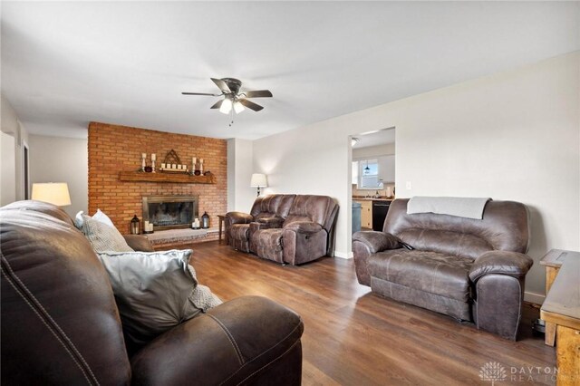 living room with wood-type flooring, a brick fireplace, and ceiling fan