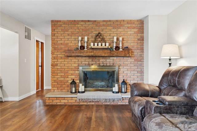 living room featuring wood-type flooring and a brick fireplace