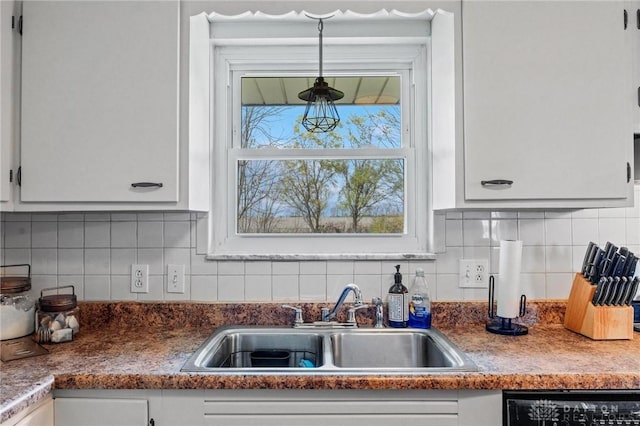 kitchen with backsplash, dishwashing machine, white cabinetry, and sink