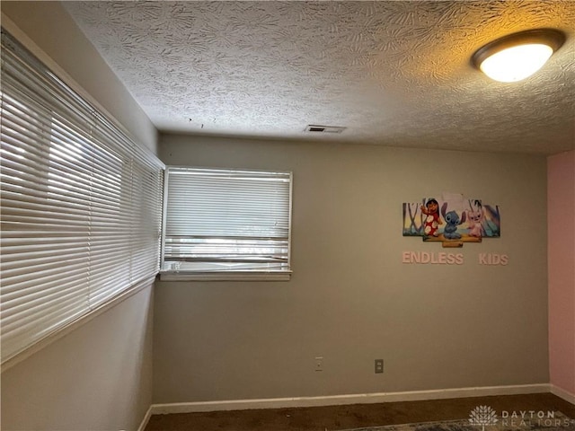 carpeted empty room featuring a textured ceiling