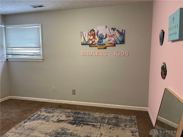 empty room with a textured ceiling and dark colored carpet