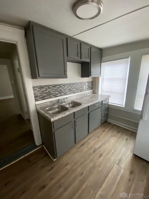 kitchen featuring gray cabinetry, decorative backsplash, sink, and light hardwood / wood-style flooring