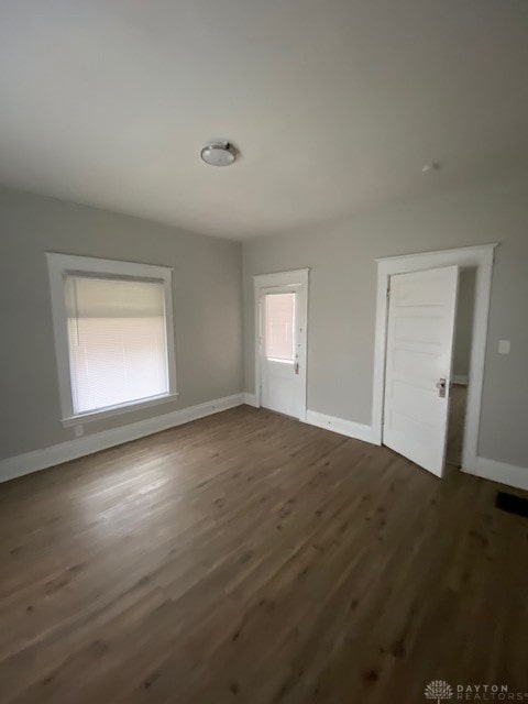 empty room featuring a healthy amount of sunlight and dark hardwood / wood-style floors