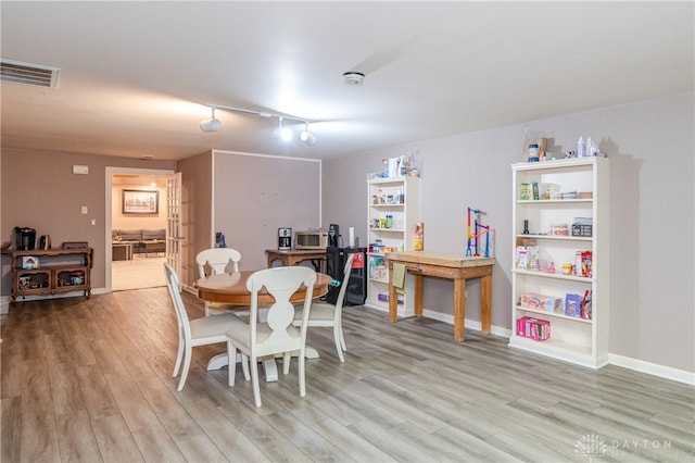 dining room with track lighting and light wood-type flooring