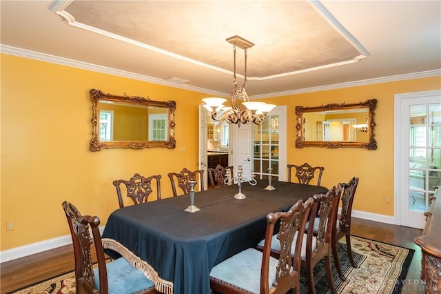 dining area with a raised ceiling, hardwood / wood-style floors, a notable chandelier, and ornamental molding