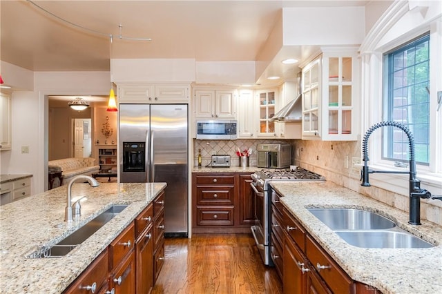 kitchen with backsplash, stainless steel appliances, light stone counters, and sink