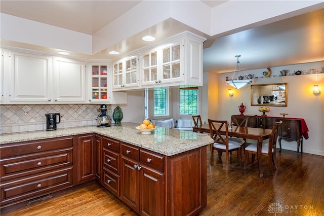 kitchen featuring light stone countertops, white cabinetry, hanging light fixtures, and hardwood / wood-style flooring