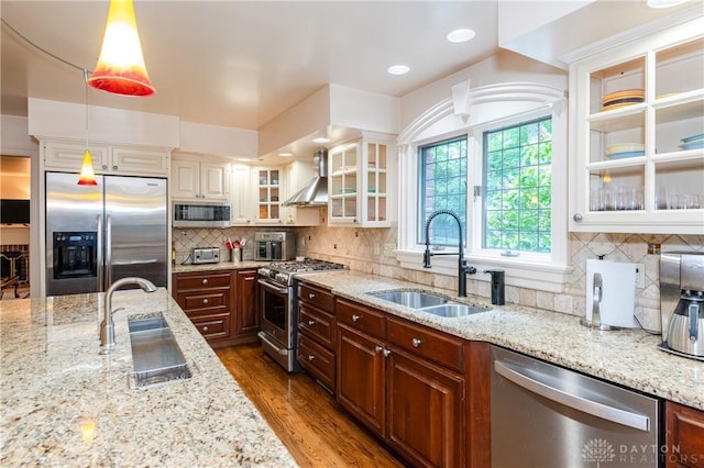 kitchen with light stone countertops, stainless steel appliances, hanging light fixtures, and sink