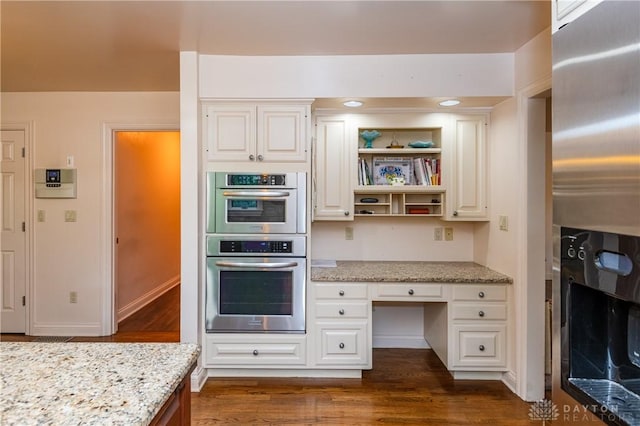 kitchen featuring white cabinetry, light stone countertops, stainless steel appliances, and dark wood-type flooring