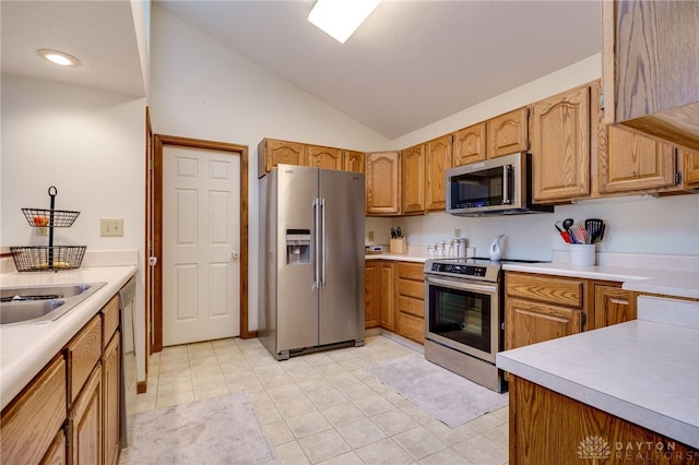 kitchen featuring light tile patterned flooring, lofted ceiling, stainless steel appliances, and sink