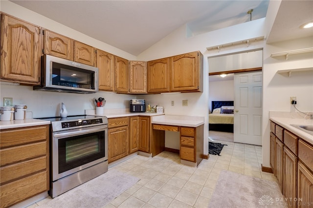 kitchen featuring lofted ceiling, sink, stainless steel appliances, and light tile patterned flooring