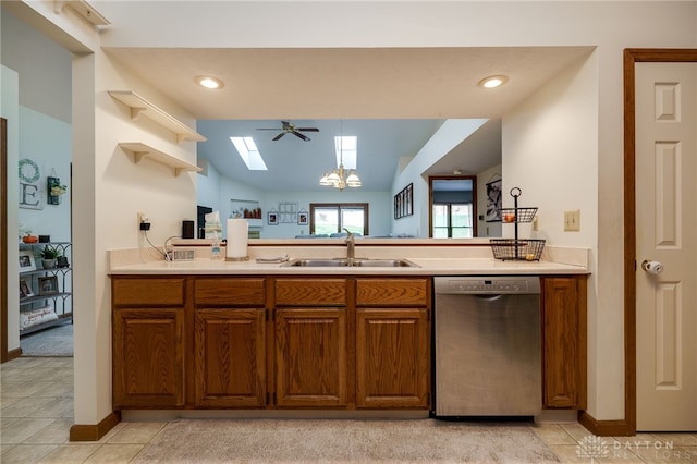 kitchen with sink, ceiling fan with notable chandelier, vaulted ceiling with skylight, decorative light fixtures, and stainless steel dishwasher