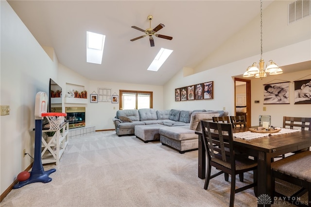 carpeted dining area with ceiling fan with notable chandelier, a fireplace, and high vaulted ceiling