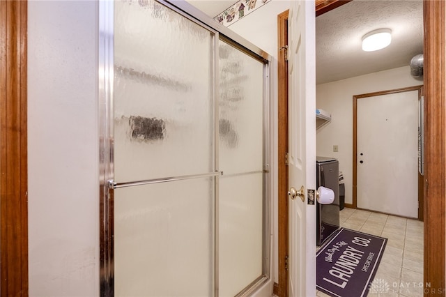 bathroom featuring tile patterned flooring, a shower with shower door, and a textured ceiling