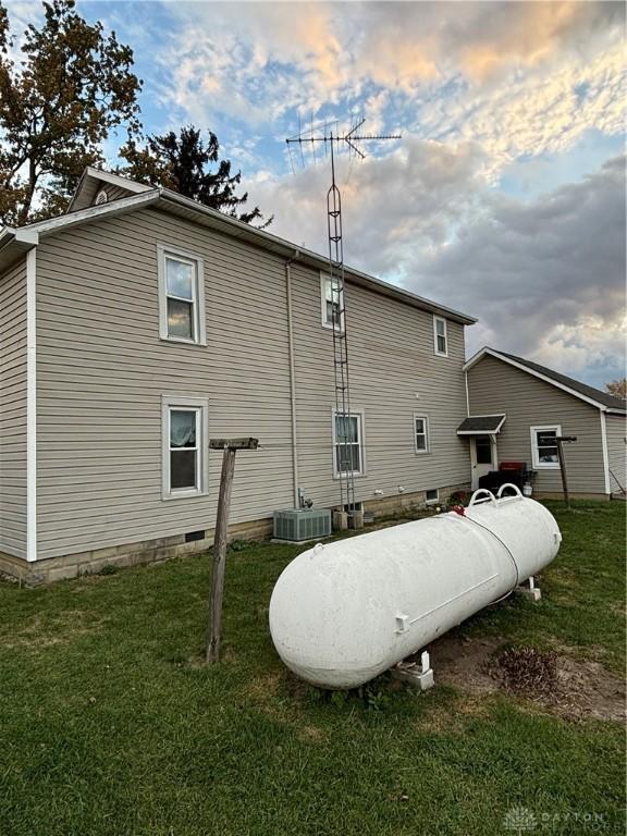 back house at dusk featuring a yard and central air condition unit