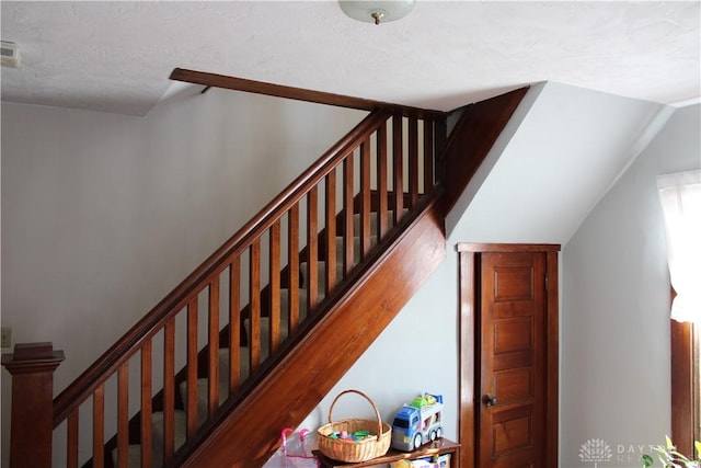 staircase with wood-type flooring and a textured ceiling