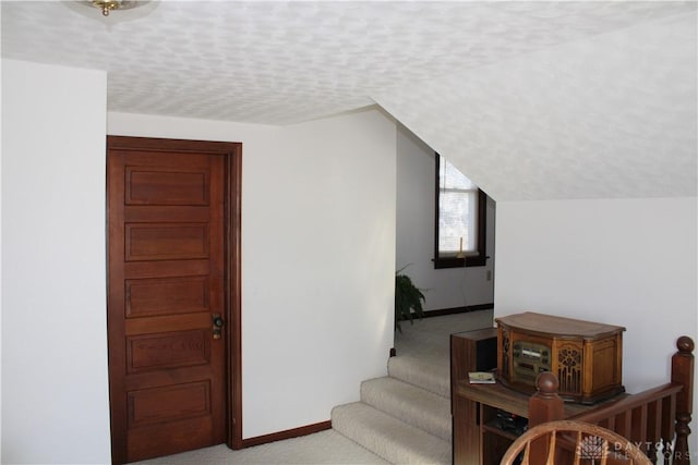 stairway featuring carpet flooring and a textured ceiling