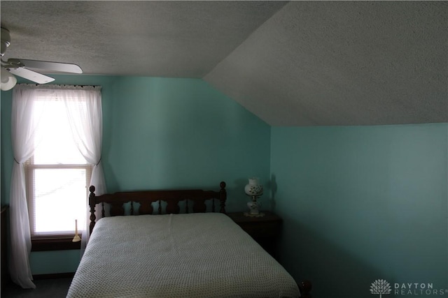 bedroom with a textured ceiling, multiple windows, ceiling fan, and lofted ceiling