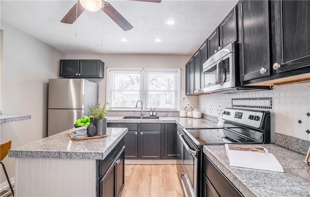 kitchen featuring ceiling fan, sink, stainless steel appliances, tasteful backsplash, and light wood-type flooring