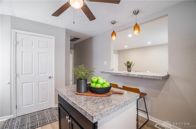 kitchen with kitchen peninsula, light wood-type flooring, a breakfast bar, and decorative light fixtures