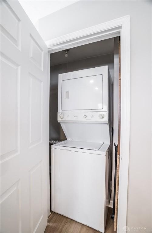 laundry room with hardwood / wood-style floors and stacked washer and dryer