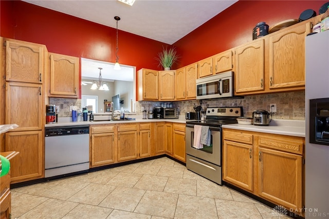 kitchen featuring appliances with stainless steel finishes, tasteful backsplash, sink, pendant lighting, and a notable chandelier