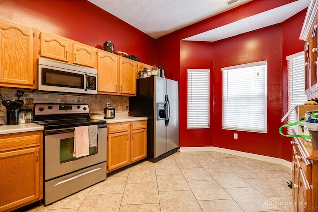 kitchen featuring backsplash, light tile patterned floors, and appliances with stainless steel finishes