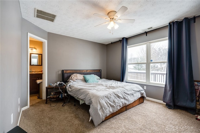 bedroom with ensuite bathroom, carpet flooring, ceiling fan, a textured ceiling, and multiple windows