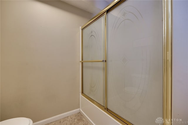 bathroom featuring bath / shower combo with glass door and toilet