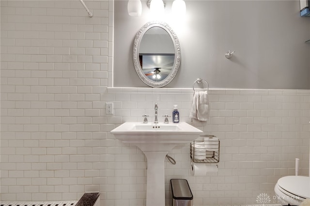 bathroom with toilet, tile walls, and tasteful backsplash