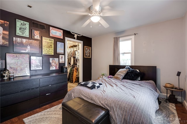 bedroom with hardwood / wood-style floors, a walk in closet, a closet, and ceiling fan