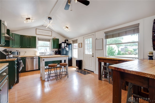 kitchen featuring vaulted ceiling, green cabinetry, ceiling fan, decorative backsplash, and stainless steel appliances