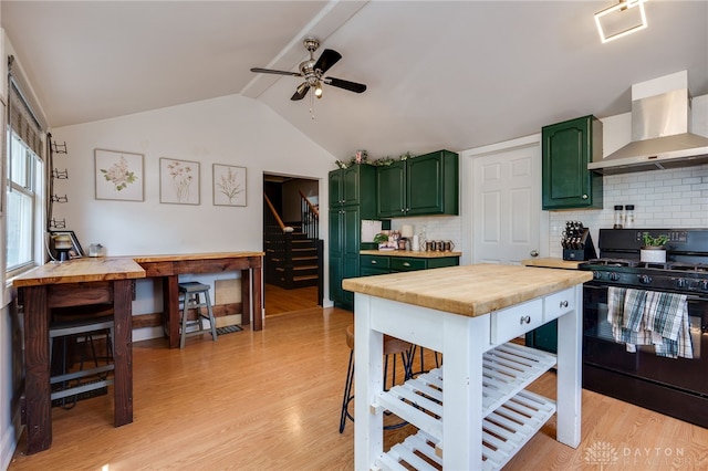 kitchen featuring wall chimney exhaust hood, black range with gas stovetop, decorative backsplash, and green cabinetry