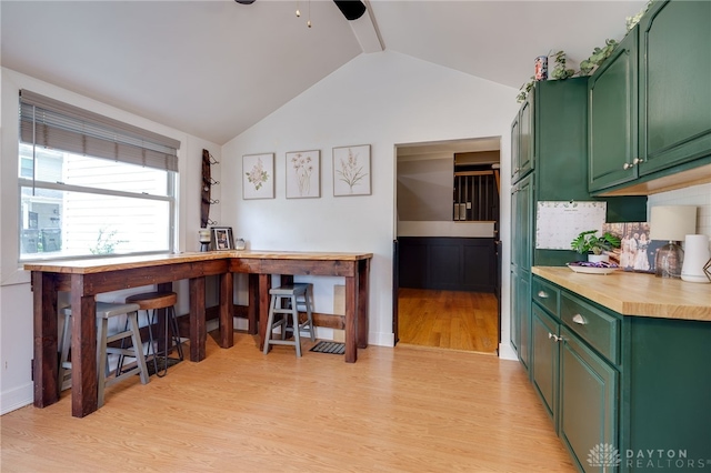 kitchen with vaulted ceiling, tasteful backsplash, light hardwood / wood-style flooring, and green cabinetry