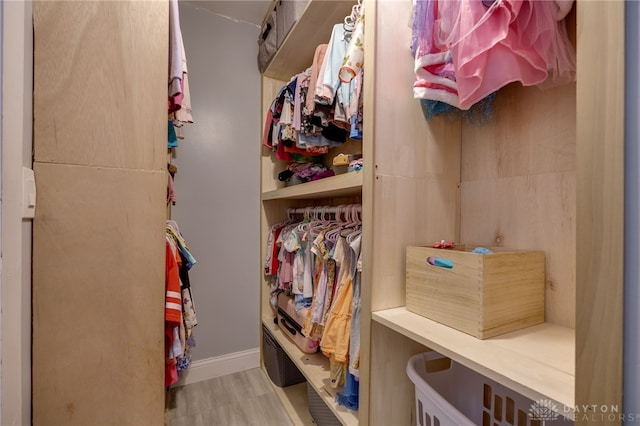 walk in closet with light hardwood / wood-style floors