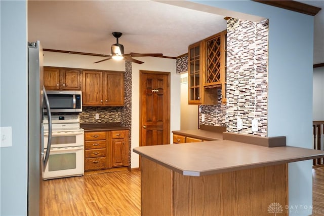 kitchen with decorative backsplash, range with two ovens, kitchen peninsula, and light hardwood / wood-style flooring