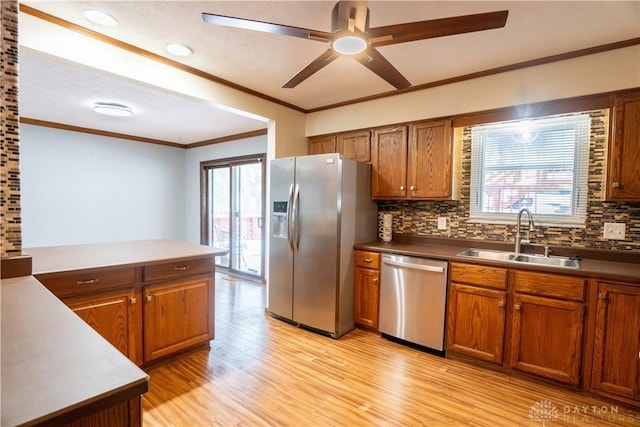 kitchen with sink, tasteful backsplash, crown molding, light wood-type flooring, and stainless steel appliances