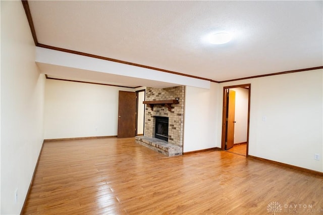 unfurnished living room featuring crown molding, a brick fireplace, and light wood-type flooring