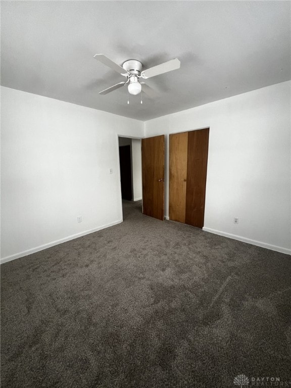 unfurnished bedroom with ceiling fan and dark carpet