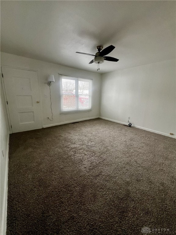 empty room featuring ceiling fan and dark colored carpet