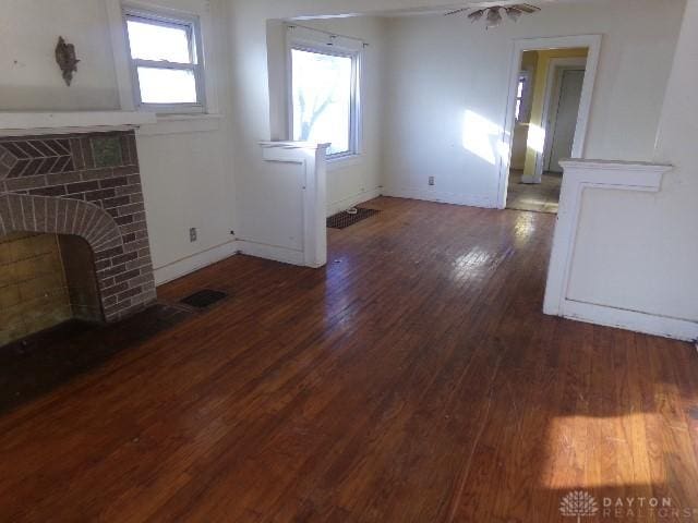 unfurnished living room featuring a fireplace, ceiling fan, and dark wood-type flooring