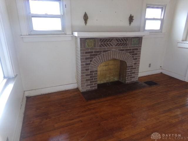 unfurnished living room with dark hardwood / wood-style floors and a brick fireplace