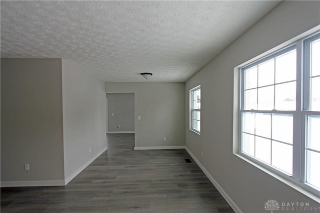 spare room featuring plenty of natural light, dark wood-type flooring, and a textured ceiling